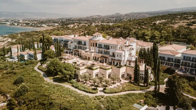 Aerial view of a large white resort hotel above the coast among greenery