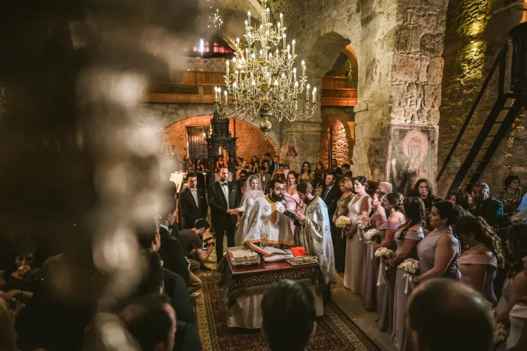 Candlelit church ceremony beneath a crystal chandelier, full of guests