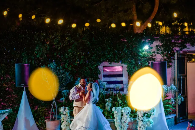 Couple's first dance framed by glowing coloured lights and white flowers