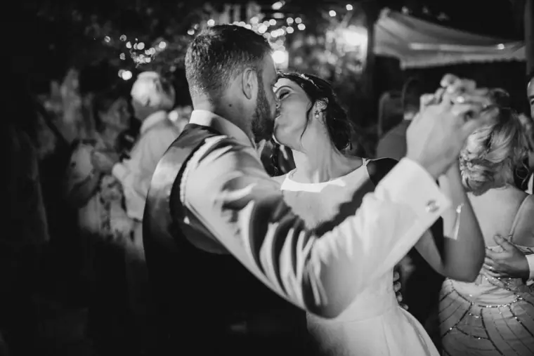Black-and-white photo of the couple dancing close among guests