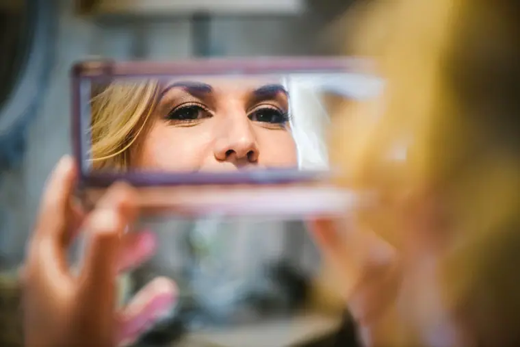 Woman's eyes reflected in a small compact mirror during make-up
