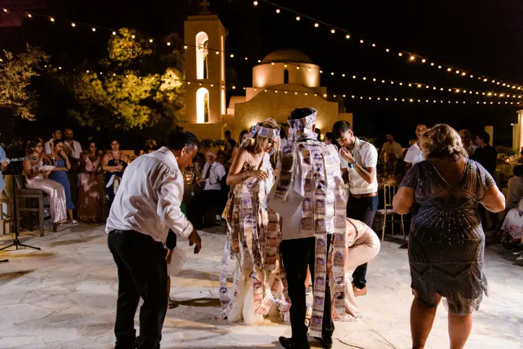 Couple dancing with banknotes pinned to their clothes as guests join in