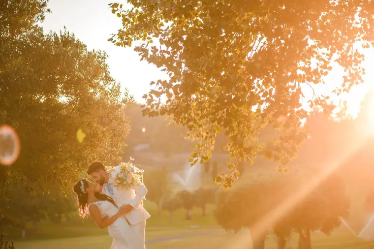 Couple embracing in a golden sunlit park with flare through the trees
