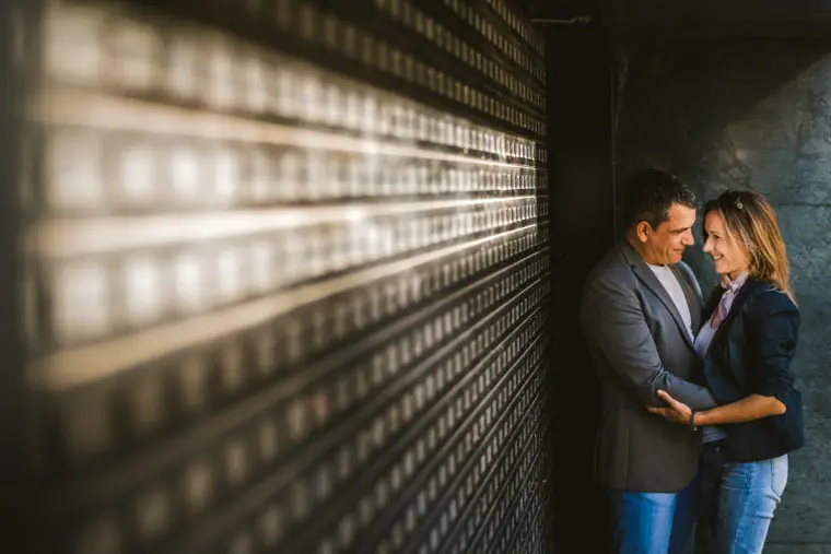 Couple in casual clothes embracing beside a slatted metal wall