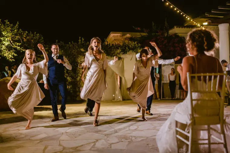 Bridesmaids and guests dancing energetically on a terrace at night