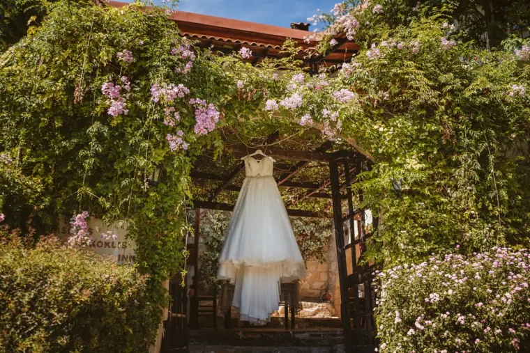 Wedding dress hanging in a flower-covered pergola at Vasilias Nikoklis Inn