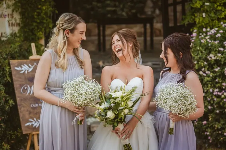 Hannah laughing with bridesmaids in lilac holding gypsophila bouquets