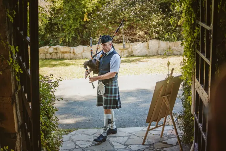 Bagpiper in a kilt playing at the entrance gate of Vasilias Nikoklis Inn