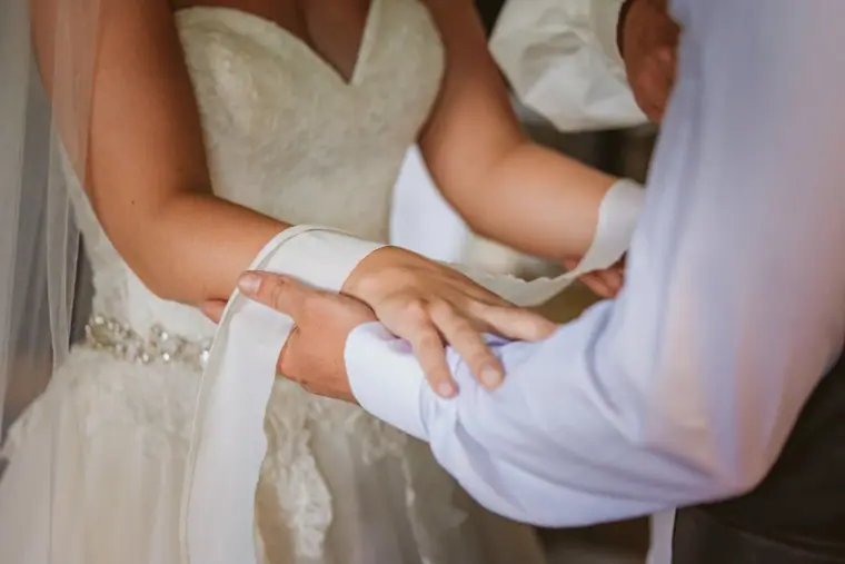 Close-up of the bride's hand on her father's arm as they walk to the ceremony