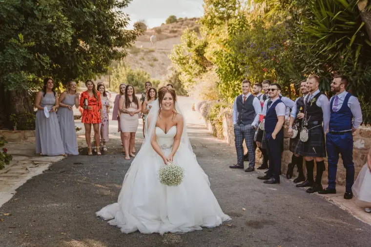 Hannah poised to throw her bouquet as guests line both sides of the driveway