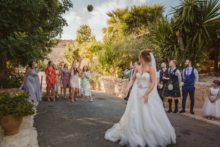 Hannah turning to watch the bouquet fly as guests reach to catch it