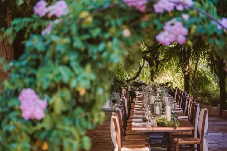 Long reception tables beneath purple blossom in a shaded courtyard at Vasilias Nikoklis Inn
