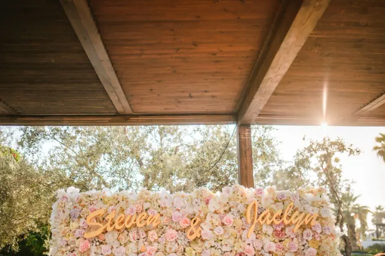 Floral wall spelling the couple's names framed by a timber canopy at Almyra, Paphos