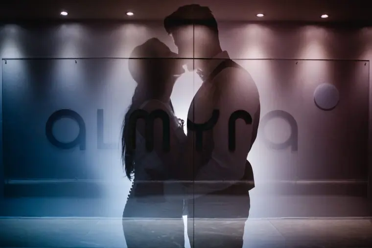 Silhouette of Jaclyn and Steven kissing against the illuminated Almyra sign