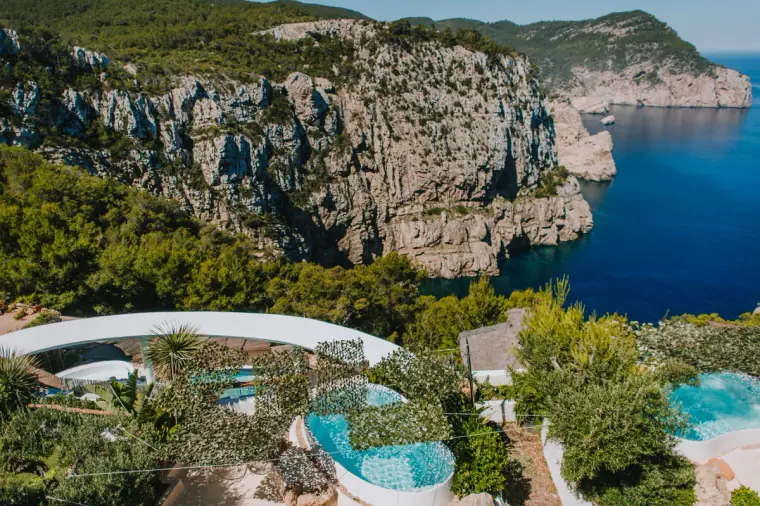 Aerial view of a clifftop villa with pools above a rugged coastline in Ibiza