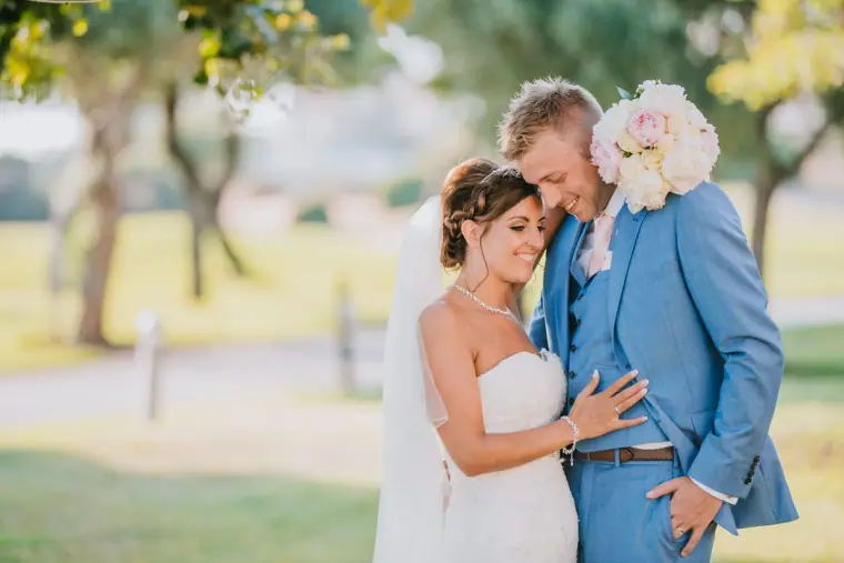 Terri and Grant cuddling on the lawn at Aphrodite Hills, Paphos, peonies on his shoulder