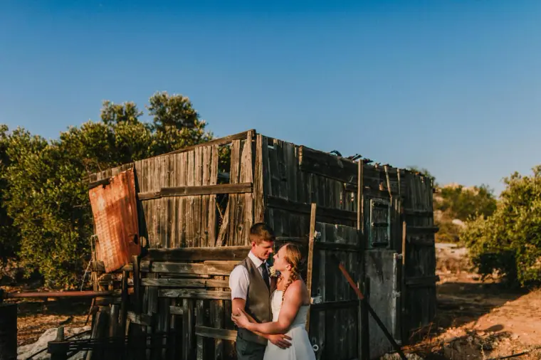 Couple in front of a weathered wooden shack during a trash-the-dress shoot near Ayia Napa