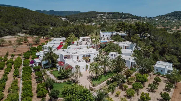 Aerial view of whitewashed Can Curreu among orange groves and hills in Ibiza