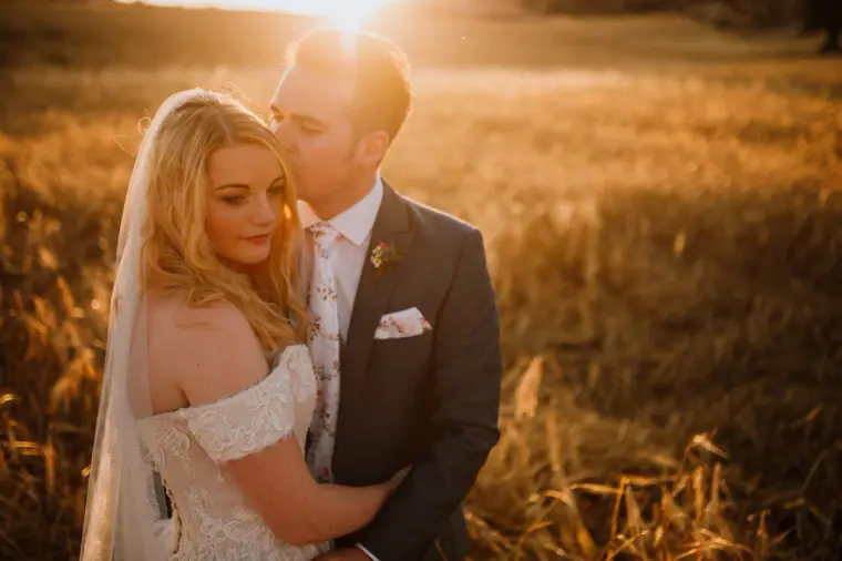 Stephanie and Jack embracing in a golden field at sunset near Vasilias Nikoklis Inn, Kouklia