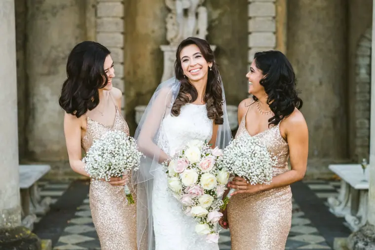 Elina with two bridesmaids in sequinned gowns holding gypsophila bouquets at Wotton House
