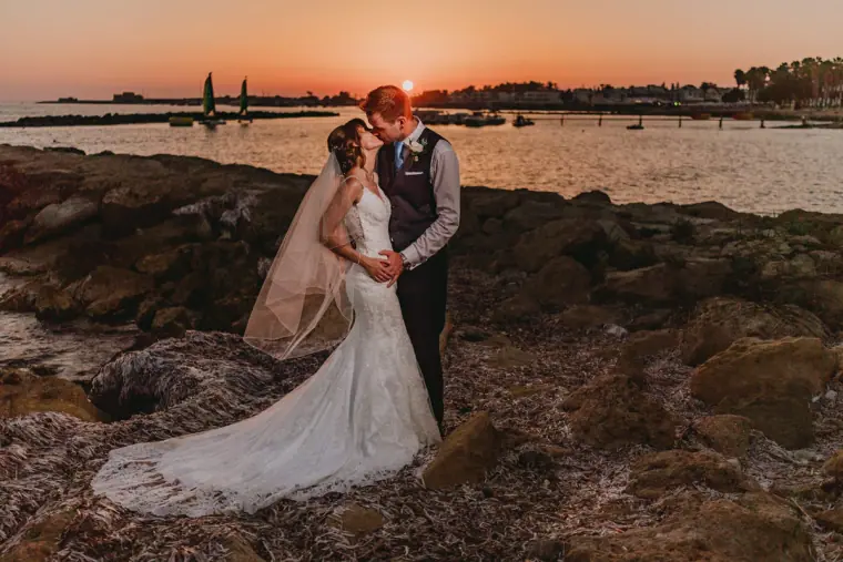 Kelly and Duncan kissing on rocks by the sea at sunset, Alexander the Great, Paphos