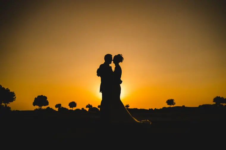 Silhouette of a couple against a glowing orange sunset at Aphrodite Hills