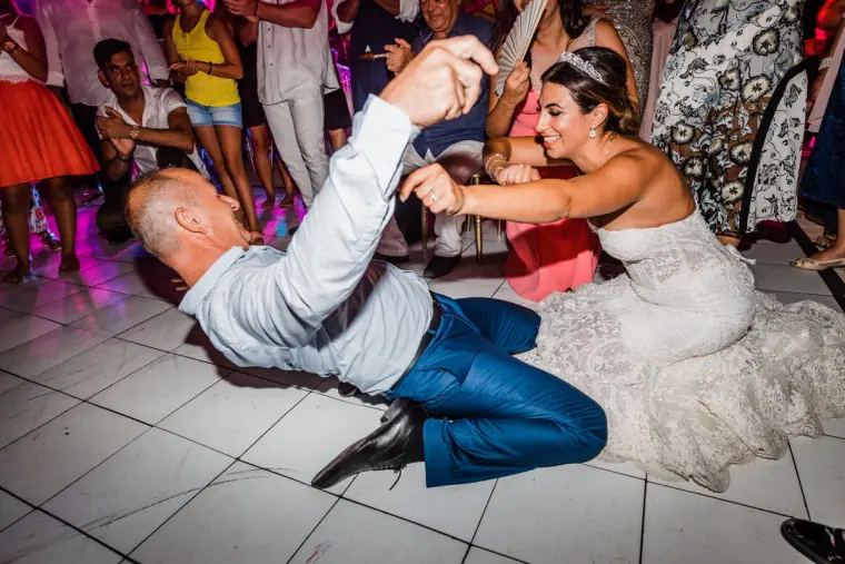 Bride and a guest sprawled laughing on the dance floor at Anassa, Cyprus