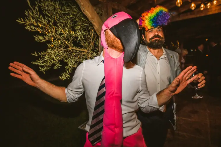 Guests in rainbow and pink party wigs dancing at night at Chateau Rigaud, France