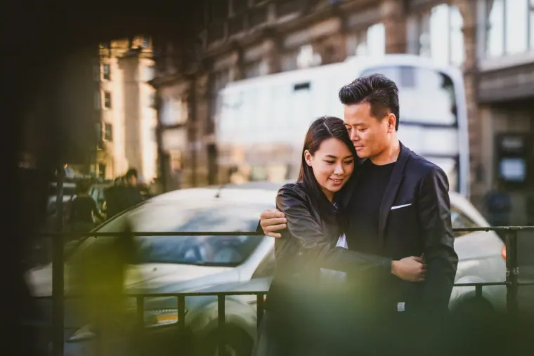 Couple embracing on a city street beside a white car in Scotland