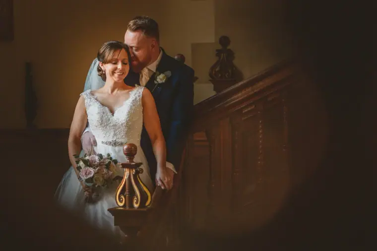 Geri and Rob standing by a carved wooden staircase at Pendley Manor