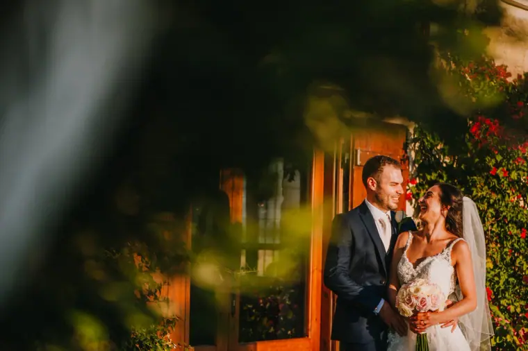 Marco and Anastassia framed by blurred foliage at a wooden door at Liopetro, Kouklia