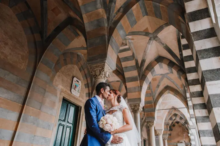 Couple kissing beneath striped Moorish arches in a cloister on the Amalfi Coast