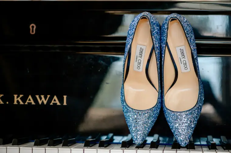 Sparkly blue Jimmy Choo heels resting on the keys of a Kawai piano, Paphos