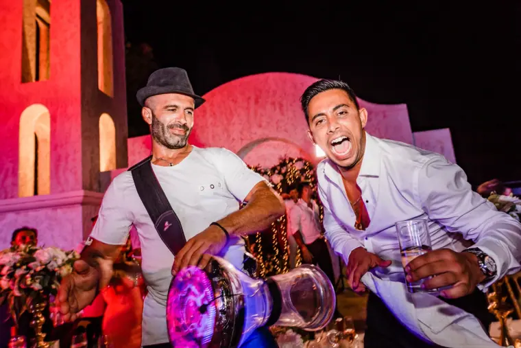 Two guests laughing and dancing at a colourful night-time party at Anassa