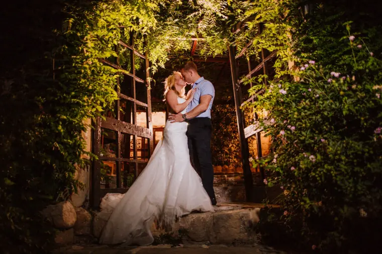 Couple embracing beneath a vine-covered pergola lit at night, Vasilias Nikoklis Inn