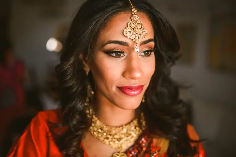 Raya in a gold maang tikka and necklace glancing over her shoulder, Ayia Napa