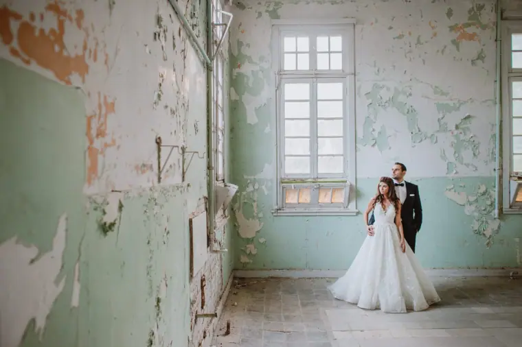 Couple standing in a derelict room with peeling mint-green walls, Limassol