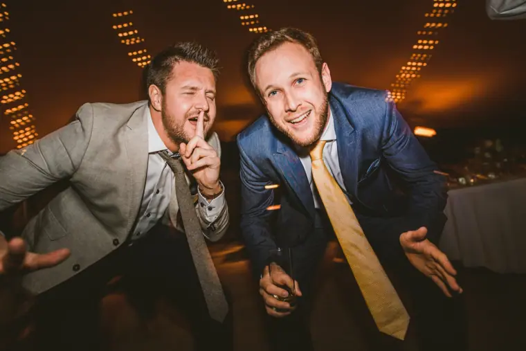 Two guests in suits playfully shushing the camera at Lexeko Estate