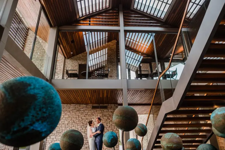 Kaye and Matt in a timber atrium with copper globe sculptures at Minthis Hills, Paphos