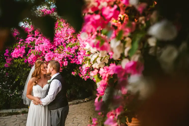 Vicky and Ian kissing beside a cascade of pink bougainvillea at Vasilias Nikoklis Inn