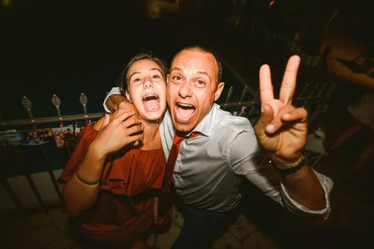Two guests pulling faces and making peace signs at an evening reception