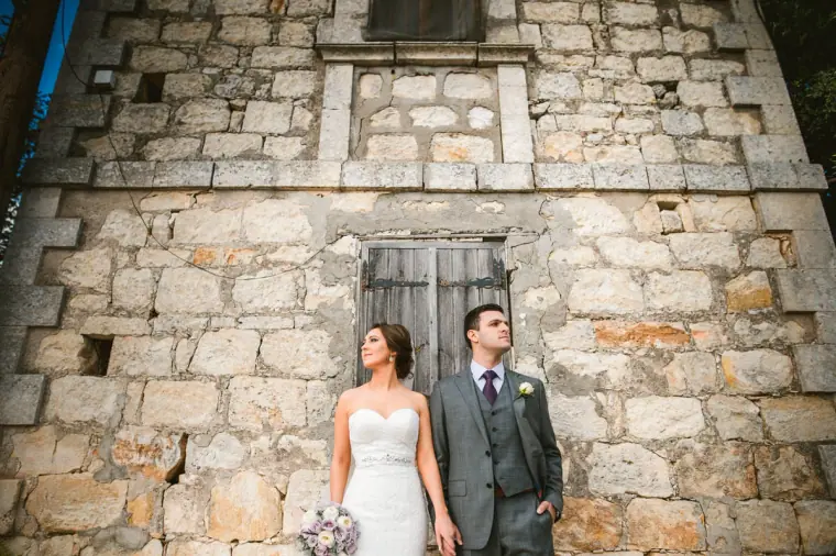 Casey and Joe standing against the weathered stone wall of an old building, Paphos
