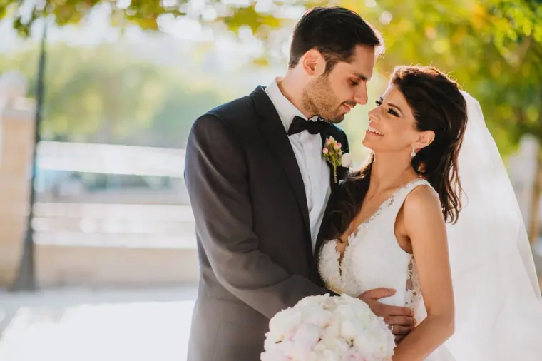 Groom in a tuxedo and smiling bride with white roses face to face, Four Seasons Limassol