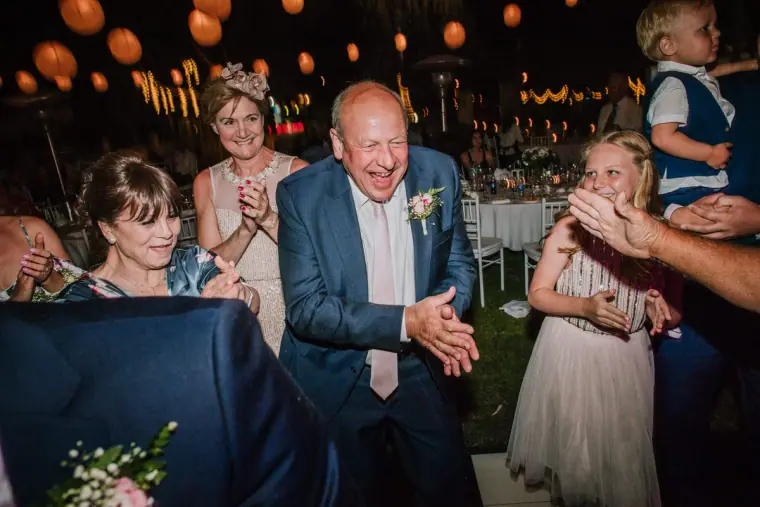 Older guests laughing at an outdoor reception under paper lanterns, Hadjiantonas Winery