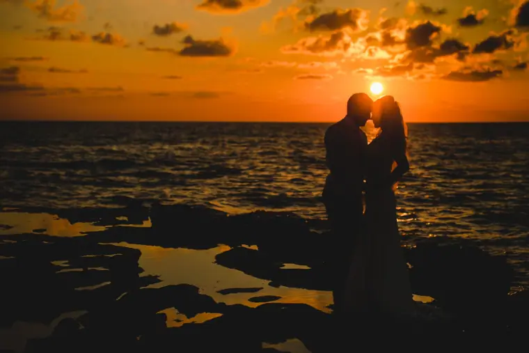 Silhouette of a couple kissing on rocks against a blazing sunset over the sea, Cyprus