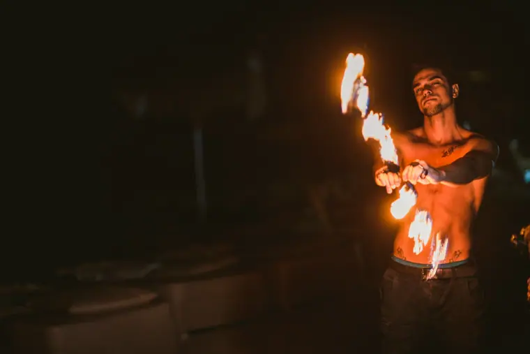 Fire performer spinning flaming batons in the dark at a reception, Ayia Napa