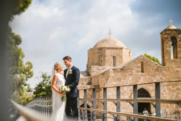 Rachel and Chris standing beside a domed stone church under a cloudy sky, Pissouri