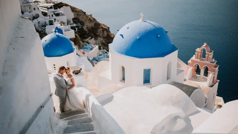 Couple embracing beside blue-domed white churches above the caldera in Santorini