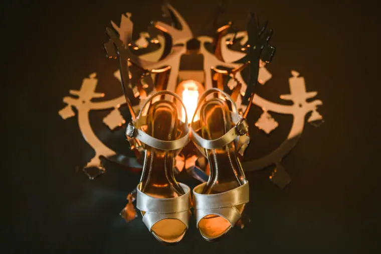 Gold bridal sandals hanging from a candlelit iron candelabra at Chateau Rigaud