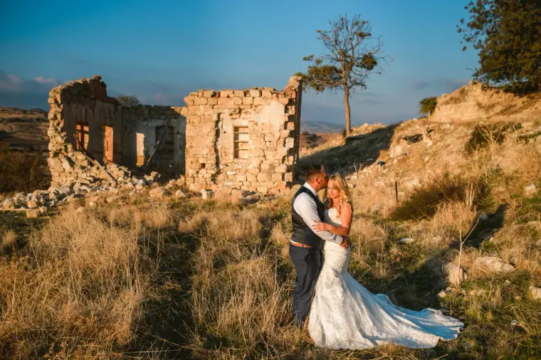 Brooke and Wayne embracing in dry grass beside stone ruins, Troodos